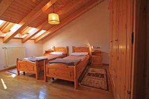 two beds in a room with wooden floors at Tony Sport appartamenti in Vigo di Fassa