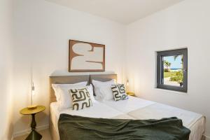 a bedroom with a bed with white sheets and a window at The Palms Seaside - Kolymvari in Kolymvari
