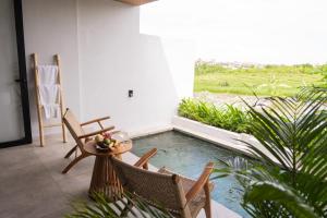 a room with a pool with chairs and a table at The Menuai Bali Villas Canggu in Canggu