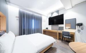 a hotel room with a bed and a desk with a television at Dangjin Dubai Hotel in Dangjin