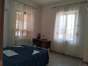 a bedroom with a bed and a desk and windows at terrazza sul castello in Roccella Ionica
