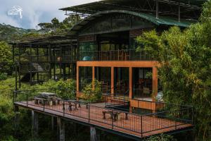 a building with a deck with trees in front of it at The Rainforest Ecolodge - Sinharaja with Shuttle Service from Car Park in Deniyaya
