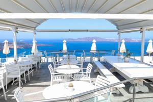 a restaurant with white tables and chairs and the ocean at Kafieris Blue in Firostefani