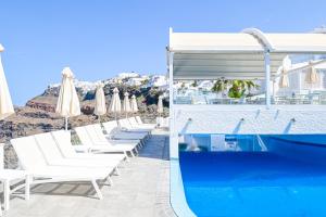 a pool with white chairs and umbrellas and a swimming pool at Kafieris Blue in Firostefani