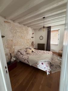 a bedroom with a bed and a stone wall at Chez leo in Marboué