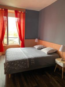 a bedroom with a bed with red curtains and a window at La Flânerie Mauriacoise in Mauriac