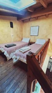 two beds in a room with wooden floors at Casa Presente Guesthouse in Carrapateira