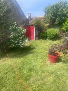 a garden with a red pot in the grass at Chez leo in Marboué