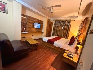 a bedroom with a bed and a chair and a television at Hotel SP international Lucknow in Lucknow