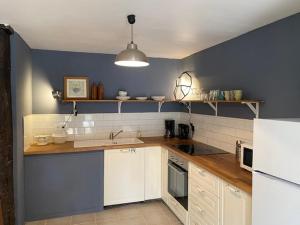 a kitchen with white cabinets and a blue wall at Le Moulin du Clapier - La Ficelle in Sorges