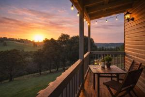 a table and chairs on a porch with a sunset at Balingup Highview Chalets in Balingup