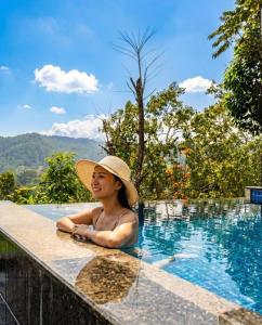a woman wearing a hat sitting in a swimming pool at Serenite Ella in Ella