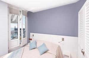 a bedroom with a bed with blue pillows and a window at Hotel Atlantique in Le Palais