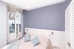 a bedroom with a bed with blue pillows and a window at Hotel Atlantique in Le Palais