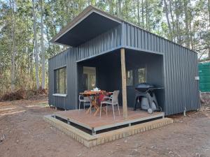 a black tiny house with a table and a grill at Zest Forest Retreat in Great Brak River
