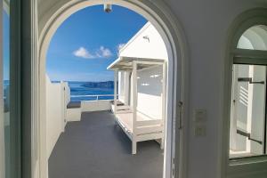 an arched doorway to a balcony with a view of the ocean at Yposkafo Suites - Studio - Santorini in Fira