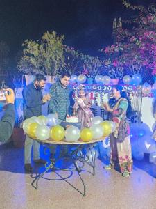a group of people standing around a table with a cake at Hotel Priyanka - 750 metres from nakki lake Near Bus Stand in Mount Ābu