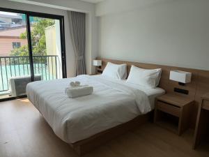 a bedroom with a large white bed with a balcony at 611 Hotel in Phetchaburi +8 photos