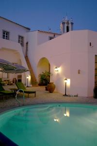 a swimming pool in front of a house with a building at Casa de Estoi in Estói