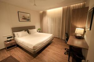 a bedroom with a bed and a desk with a lamp at Alpine Resort in Yelagiri