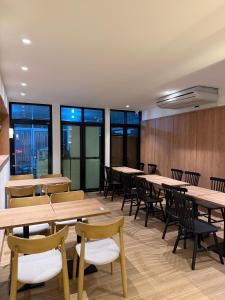 a dining room with tables and chairs and windows at 611 Hotel in Phetchaburi