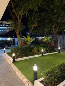 a garden with lights on the grass at night at 611 Hotel in Phetchaburi