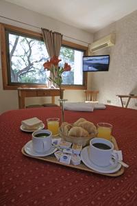 a table with a tray of food and cups of coffee at Hotel Xumec Mendoza in Mendoza