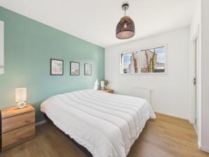 a bedroom with a white bed and a blue wall at Superbe maison récente pour 8 avec jardin in Pléneuf-Val-André