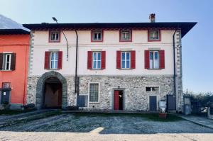 a large stone building with red shutters on it at BoscoLago apartment Lake Iseo & Franciacorta in Iseo