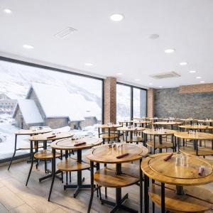 a dining room with tables and snow covered mountains at Hotel Les Neus in Pas de la Casa