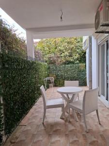 a patio with a table and chairs and a hedge at Apartments Kaludjerovic in Herceg-Novi