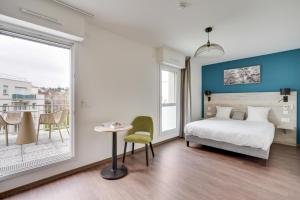 a bedroom with a bed and a table and a window at All Suites Appart Hôtel - Palaiseau - Massy TGV in Palaiseau +79 photos