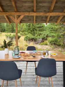a wooden table with chairs and food on a patio at Cranberry Cabin Buscat in Muntele Băişorii