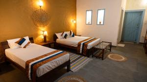 a hotel room with two beds and a door at Bardiya Nature Lodge in Belā