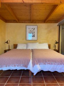 two beds in a room with a wooden ceiling at Casa Presente Guesthouse in Carrapateira