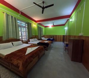 a room with three beds and green walls at Hobo's Nest in Kurseong