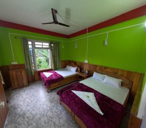 a room with two beds and a green wall at Hobo's Nest in Kurseong