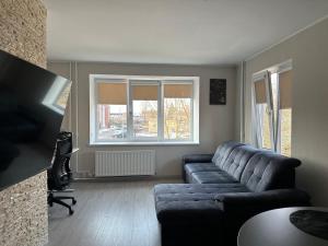 a living room with a blue couch and a window at Central Cozy Apartment in Ludza