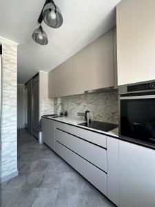 a kitchen with white cabinets and a sink at Central Cozy Apartment in Ludza