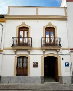 a white building with two balconies and a door at Pensión Los Arcos in Córdoba