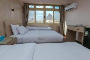 two beds in a room with a view of the pyramids at Guardian Guest House in Cairo