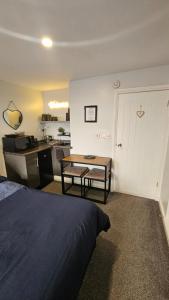 a bedroom with a bed and a table and a kitchen at Hadrians wall studio in Carlisle