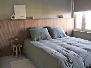 ein Schlafzimmer mit einem großen Bett mit blauen Laken und einem Hocker in der Unterkunft Moderne woning met 3 kamers voor 7 personen met gratis parking in Haaltert