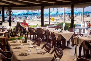 ein Restaurant mit Tischen und Leuten, die am Strand sitzen in der Unterkunft Hotel Pineta Mare in Lido di Camaiore