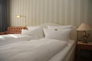 a white bed with white pillows and a red chair at Hotel Christiansen in Tinnum