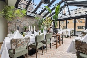 a dining room with tables and chairs and glass ceilings at Home Hotel Gabelshus in Oslo