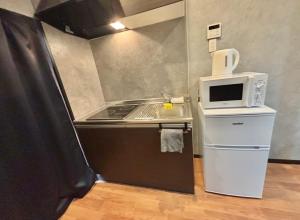 a small kitchen with a stove and a microwave at HoTTOSTAY旭 in Nishi-biwajima
