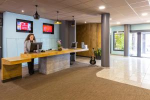 a woman standing at a desk in an office at ibis Epinal Centre in Épinal