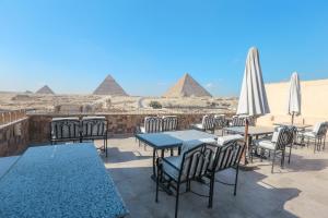 a patio with tables and chairs with pyramids in the background at Guardian Guest House in Cairo