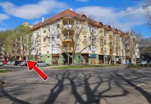 a building with a red arrow in front of a street at Lotti City Apartman in Békéscsaba